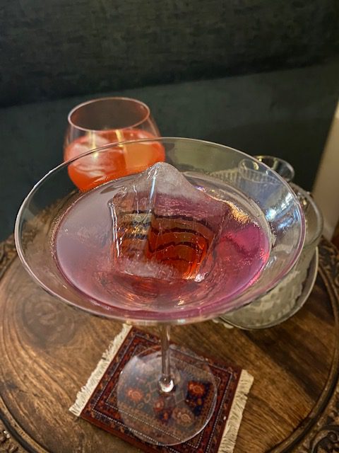 Icy Empress Gimlet: Purple haze in a cocktail glass with a large ice cube.