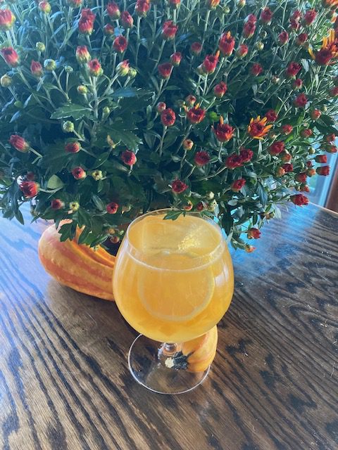 Ginger Peach n Scotch: Sunny yellow drink in a goblet with a slice of lemon and large ice cube