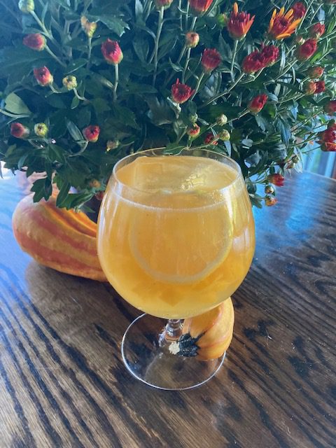Ginger Peach n Scotch: Sunny yellow drink in a goblet with a slice of lemon and large ice cube