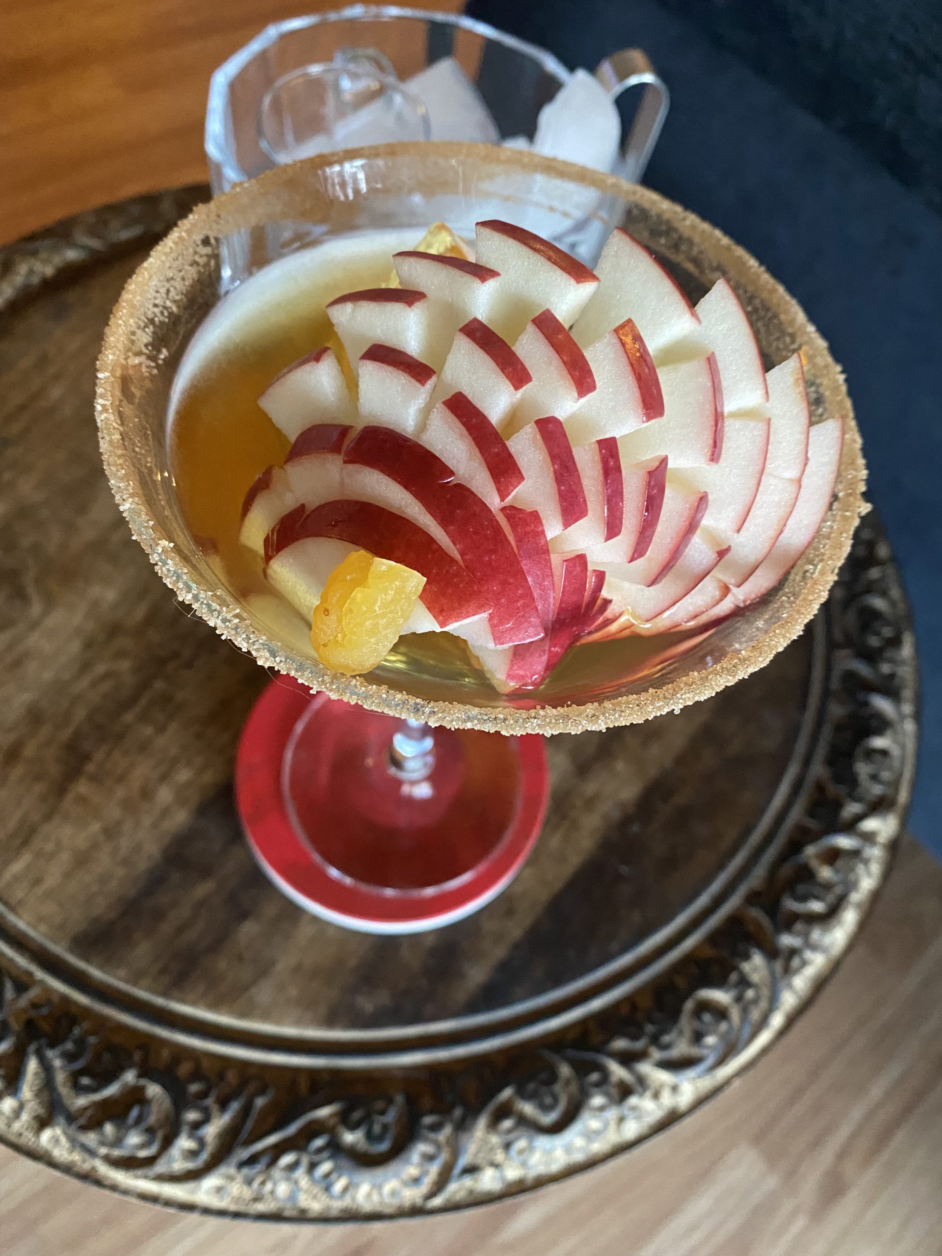 Apple Manhattan: Amber cocktail with a cinnamon-sugar rim and elaborately carved apple and tiny piece of candied ginger