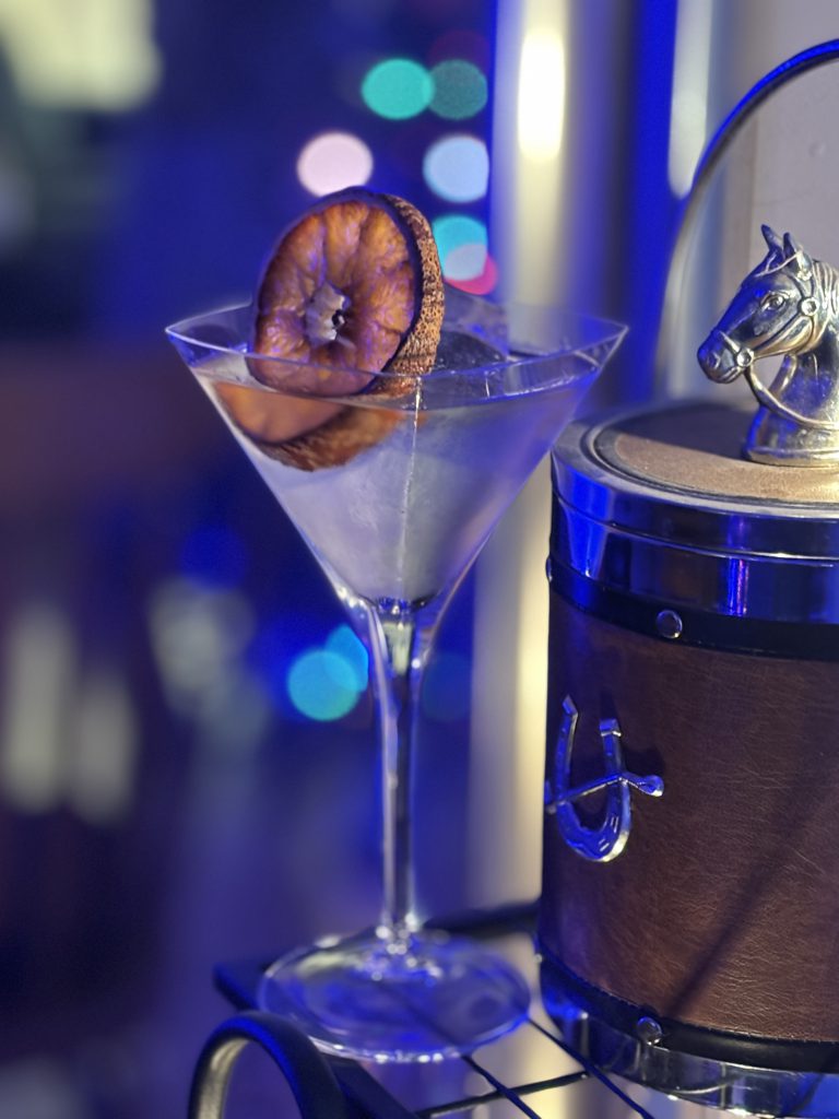 Quiet Celebration Martini: Clear cocktail with a dried citrus wheel and clear large ice cube