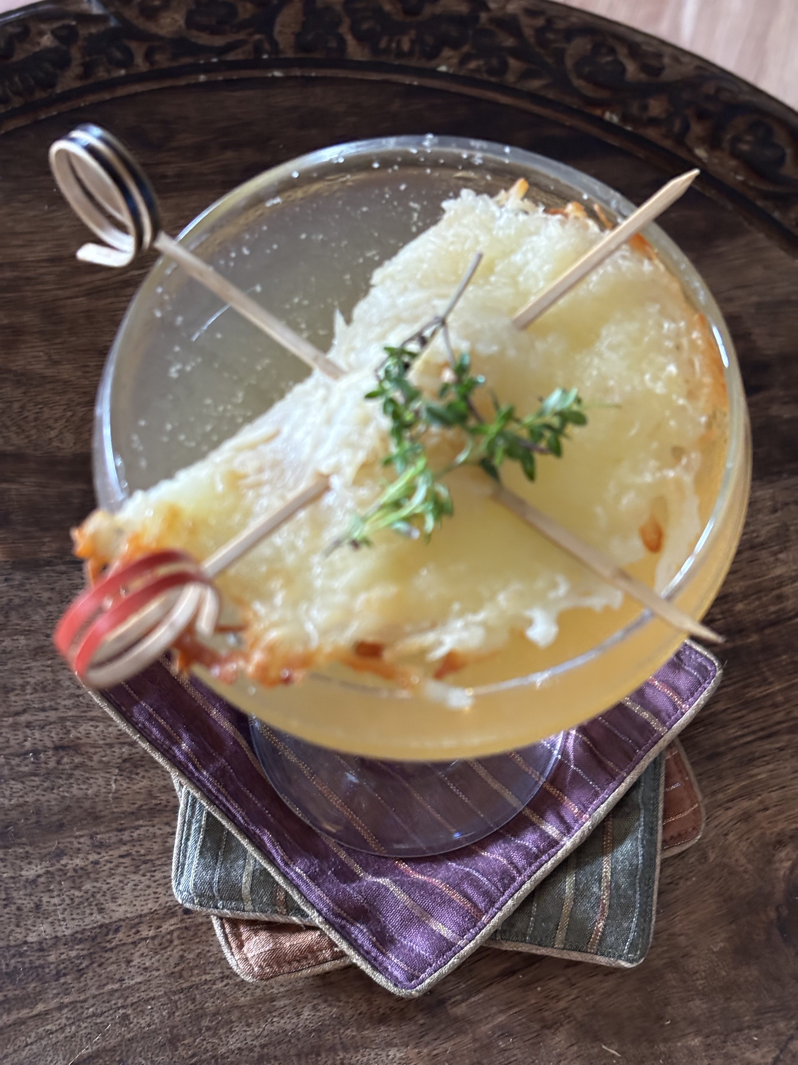 French Onion Soup: Pale yellow cocktailo in a coupe garnished with a cheese pocket and fresh thyme